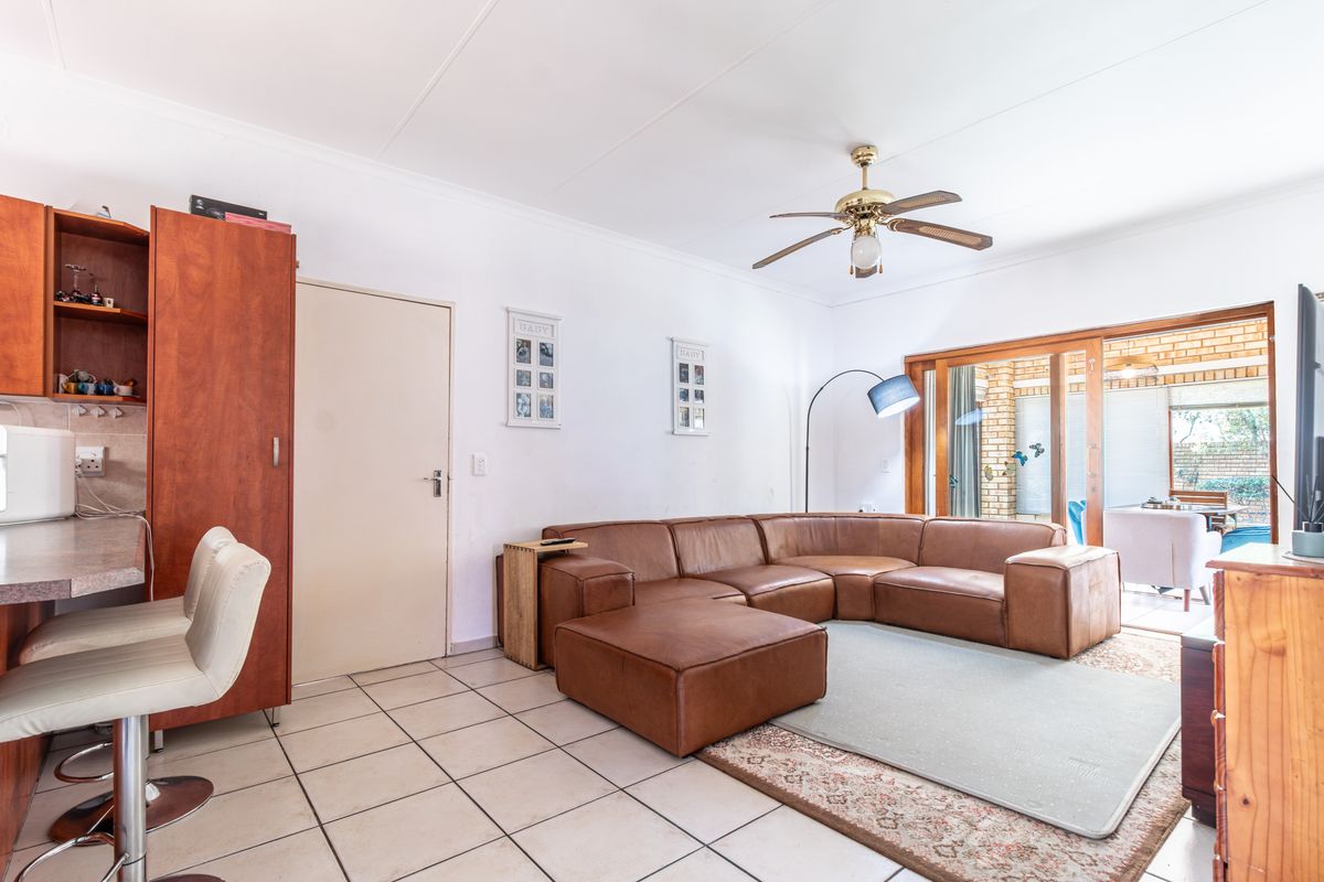 Spacious living room featuring tiled flooring, a ceiling fan, and large sliding glass doors that provide access to the outdoor patio area.
