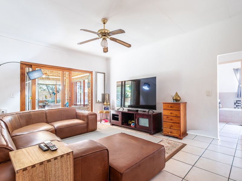 Spacious living room featuring tiled flooring, a ceiling fan, and large sliding glass doors providing access to the outdoor patio area.