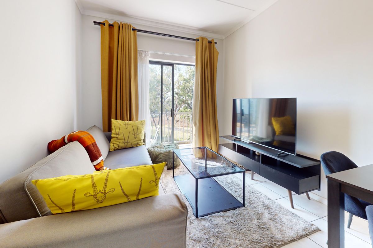 A bright living room featuring tiled flooring and a sliding glass door that provides access to an outdoor balcony area.