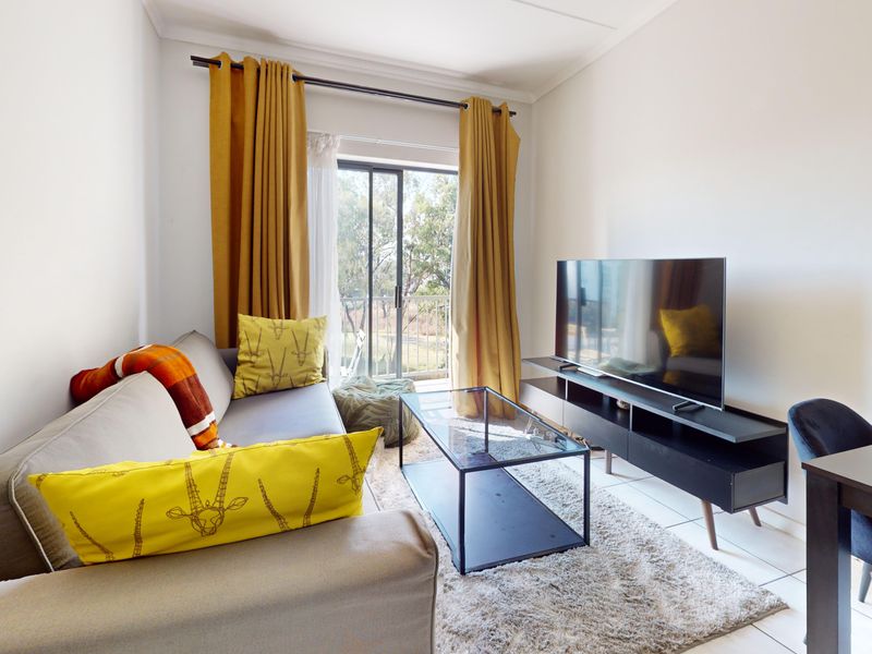 A bright living room featuring tiled flooring and a sliding glass door that provides access to an outdoor balcony area.