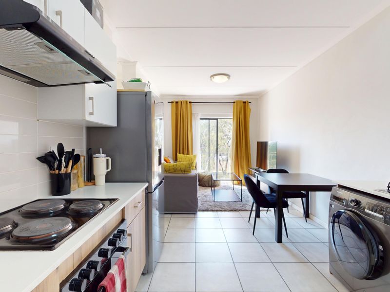 Open-plan kitchen and living area featuring tiled flooring, modern cabinetry, built-in appliances, and a sliding door leading to an outdoor space.