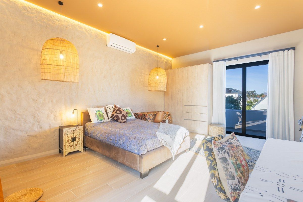 A modern, well-lit bedroom featuring a textured accent wall, built-in cabinetry, recessed lighting, and sliding glass doors leading to a private balcony.