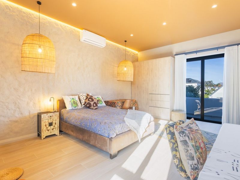 A modern, well-lit bedroom featuring a textured accent wall, built-in cabinetry, recessed lighting, and sliding glass doors leading to a private balcony.