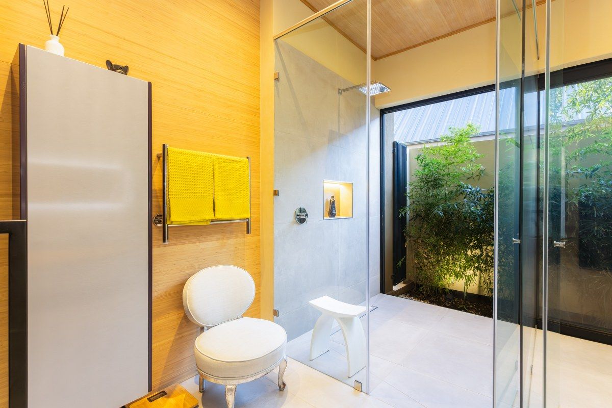 Modern bathroom featuring a walk-in glass shower, timber-look wall paneling, and a private internal courtyard with lush greenery.