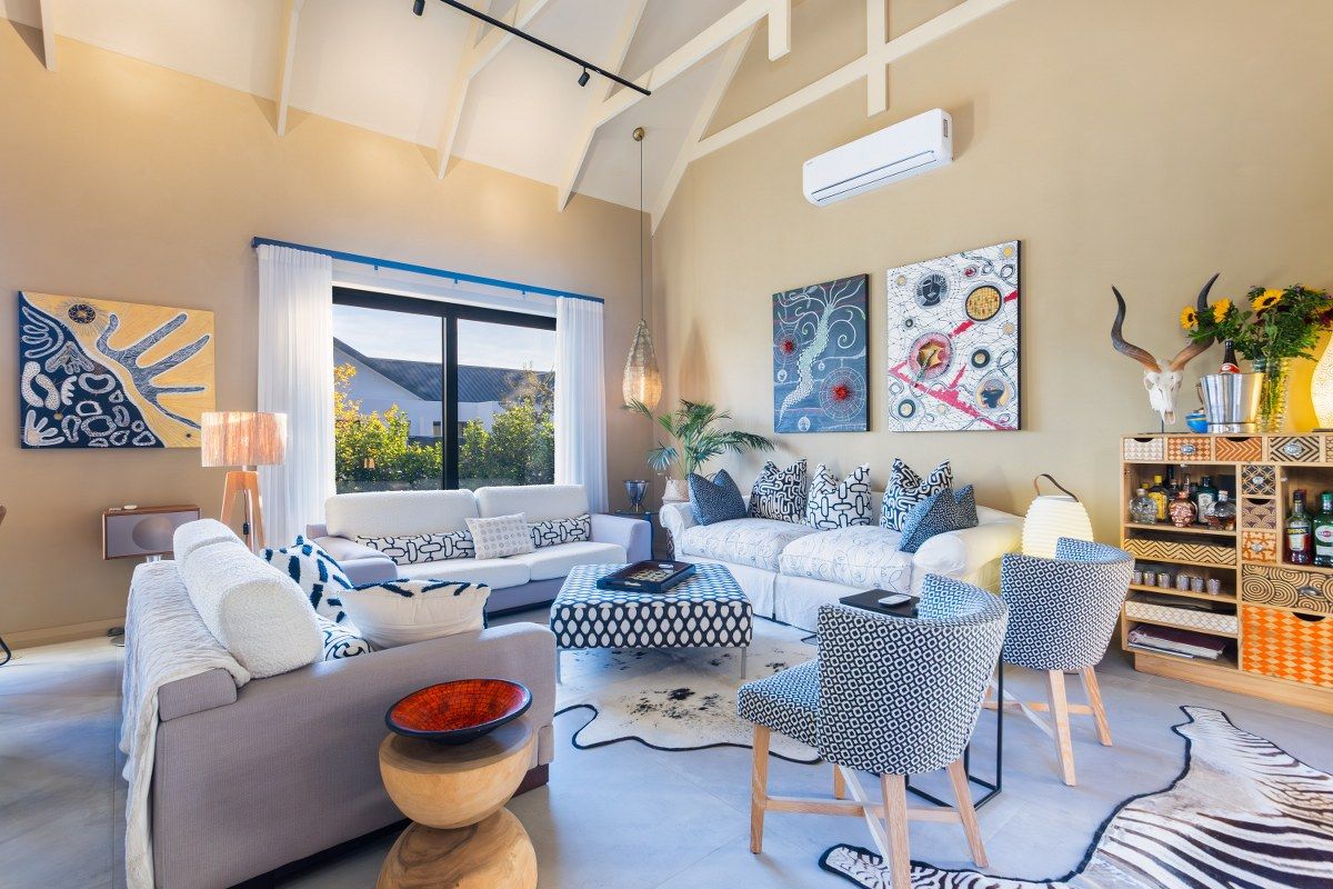 Spacious living room featuring high vaulted ceilings with exposed beams, large windows, and a wall-mounted air conditioning unit.