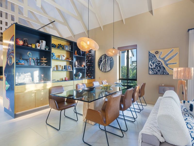 Open-plan living and dining area featuring a vaulted ceiling, tiled flooring, and a large custom built-in display cabinet with integrated shelving.