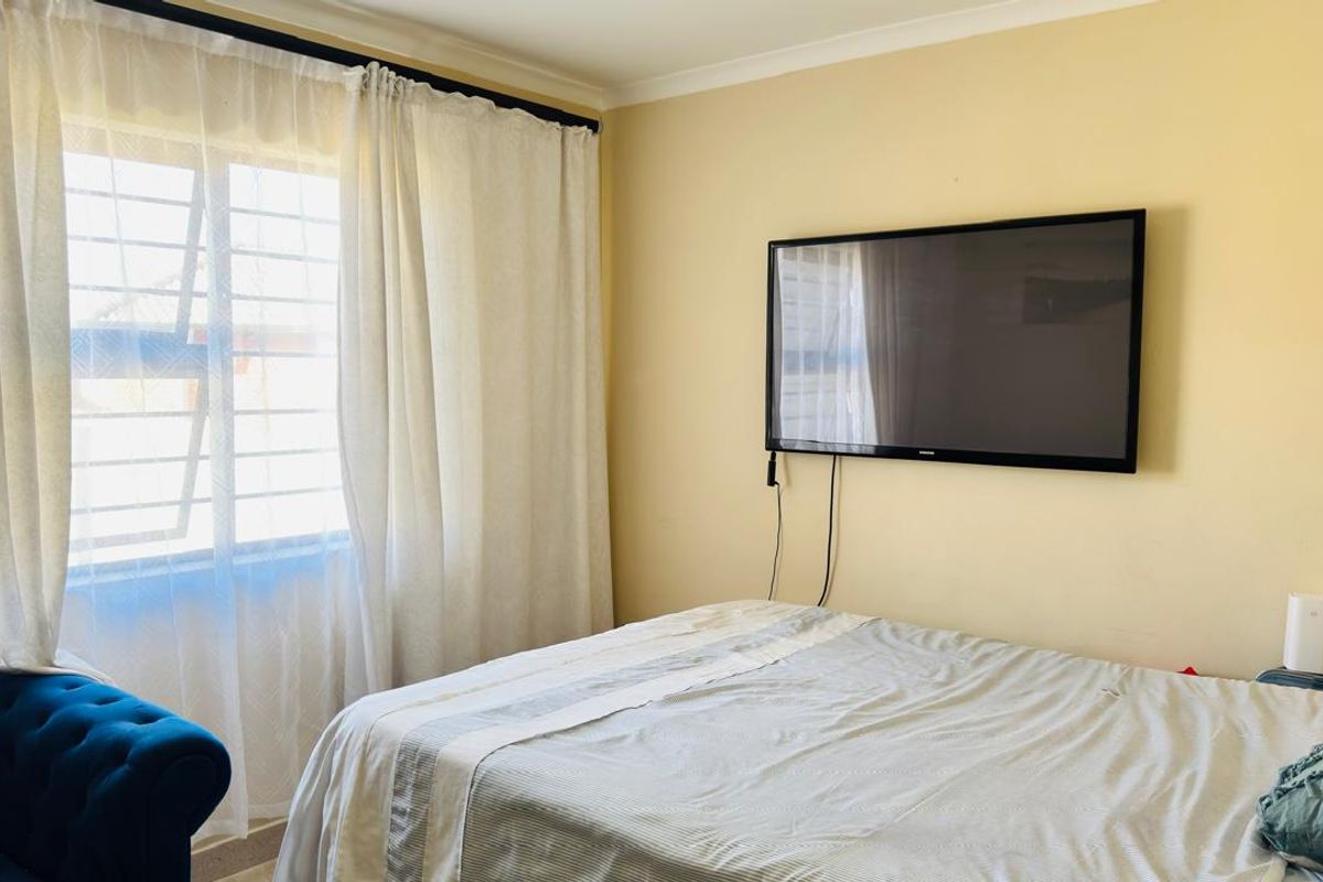 A standard bedroom featuring a window with security bars and coving detail.