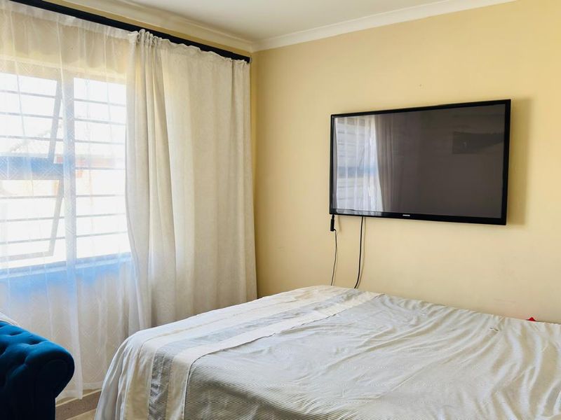 A standard bedroom featuring a window with security bars and coving detail.