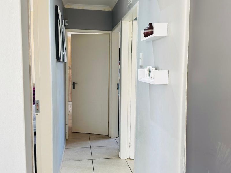 A functional hallway featuring neutral wall tones and tiled flooring, providing access to multiple rooms within the home.