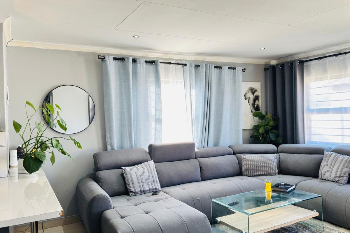 A comfortable living room featuring tiled flooring and recessed downlights, creating a bright and inviting space for relaxation.