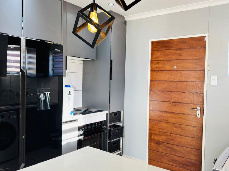 Modern kitchen featuring sleek grey cabinetry, built-in oven and hob, and a solid wood door, offering a contemporary and functional cooking space.
