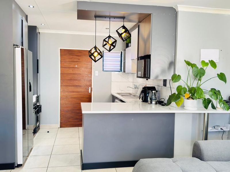 Modern open-plan kitchen featuring sleek grey cabinetry, stone countertops, and contemporary pendant lighting, seamlessly integrated with the living area.