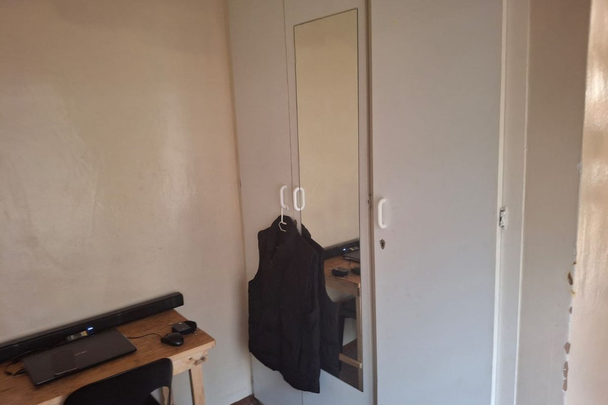 A bedroom featuring a built-in wardrobe with a mirrored panel, providing functional storage space within the room.