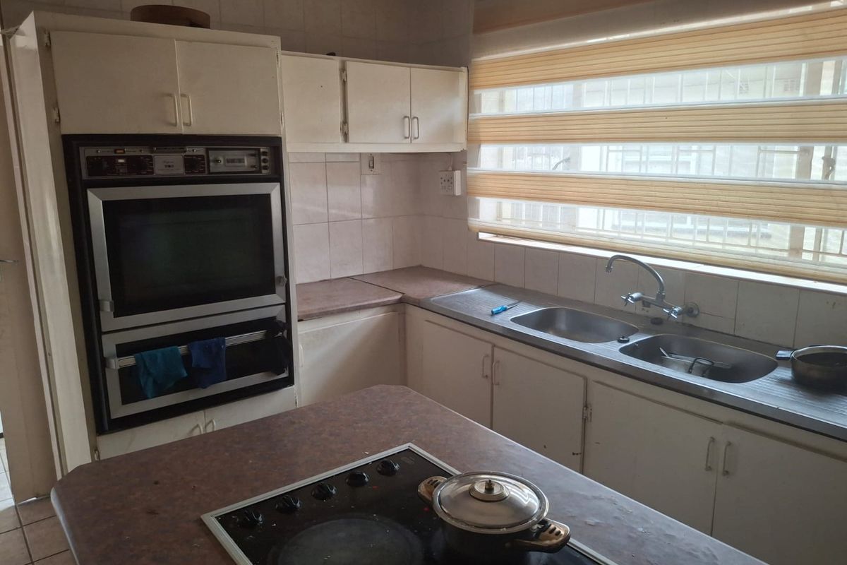 A functional kitchen featuring a built-in double oven, electric hob, double sink, and ample cabinetry, offering potential for a modern renovation.