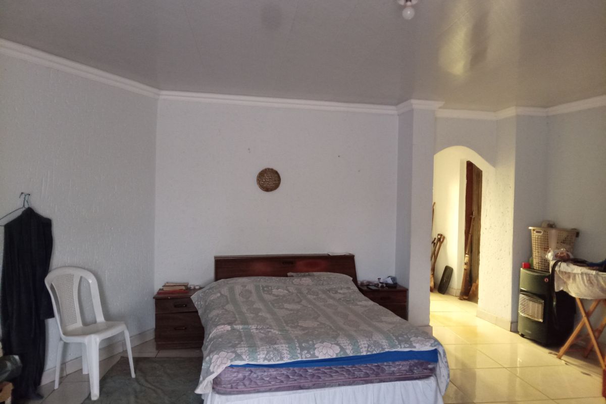 A bedroom featuring tiled flooring, crown molding, and an arched doorway leading to an adjacent space.