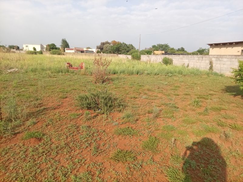 A large, undeveloped plot of land featuring a perimeter boundary wall and natural, unmaintained ground cover.