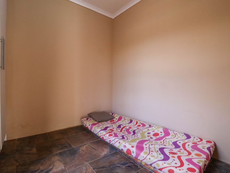A simple bedroom featuring tiled flooring, neutral wall finishes, and a built-in cupboard.