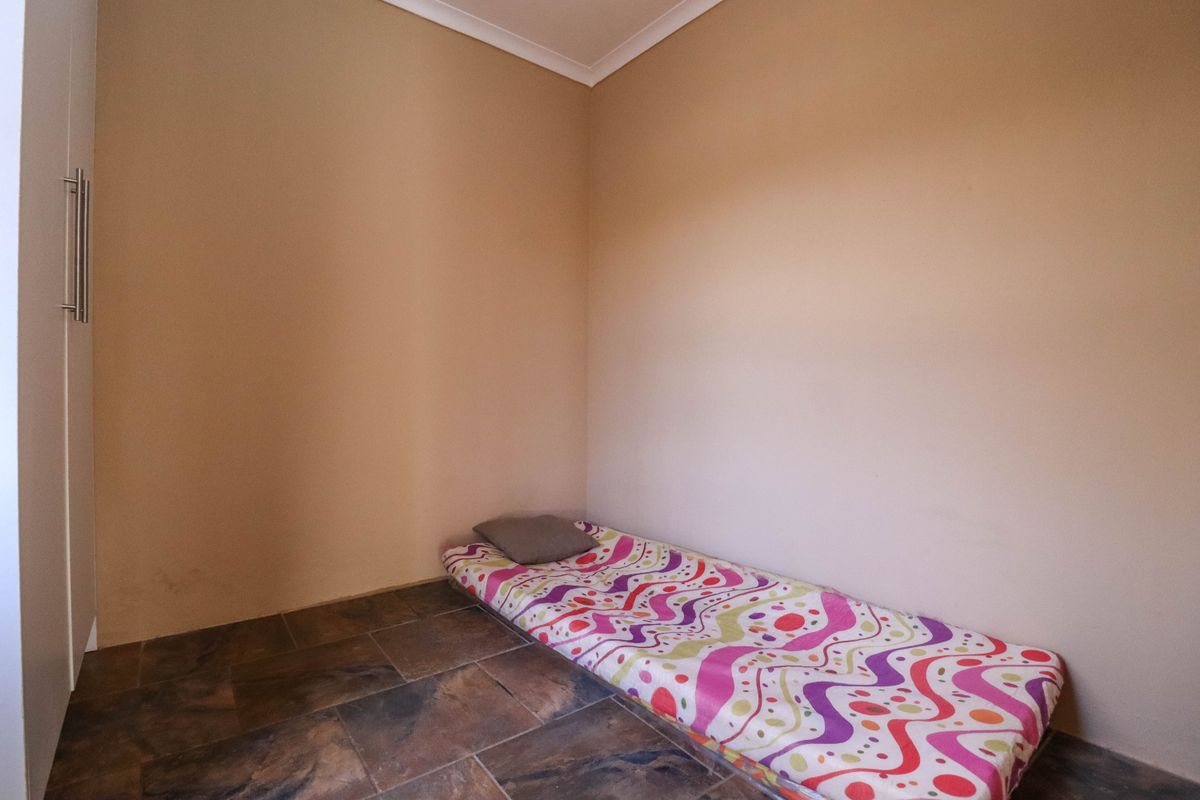 A simple bedroom featuring tiled flooring, neutral wall finishes, and a built-in cupboard.