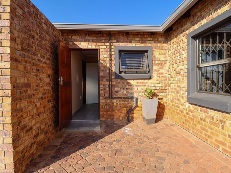 A private rear courtyard featuring face brick walls, paved flooring, and direct access to the interior through a timber door.