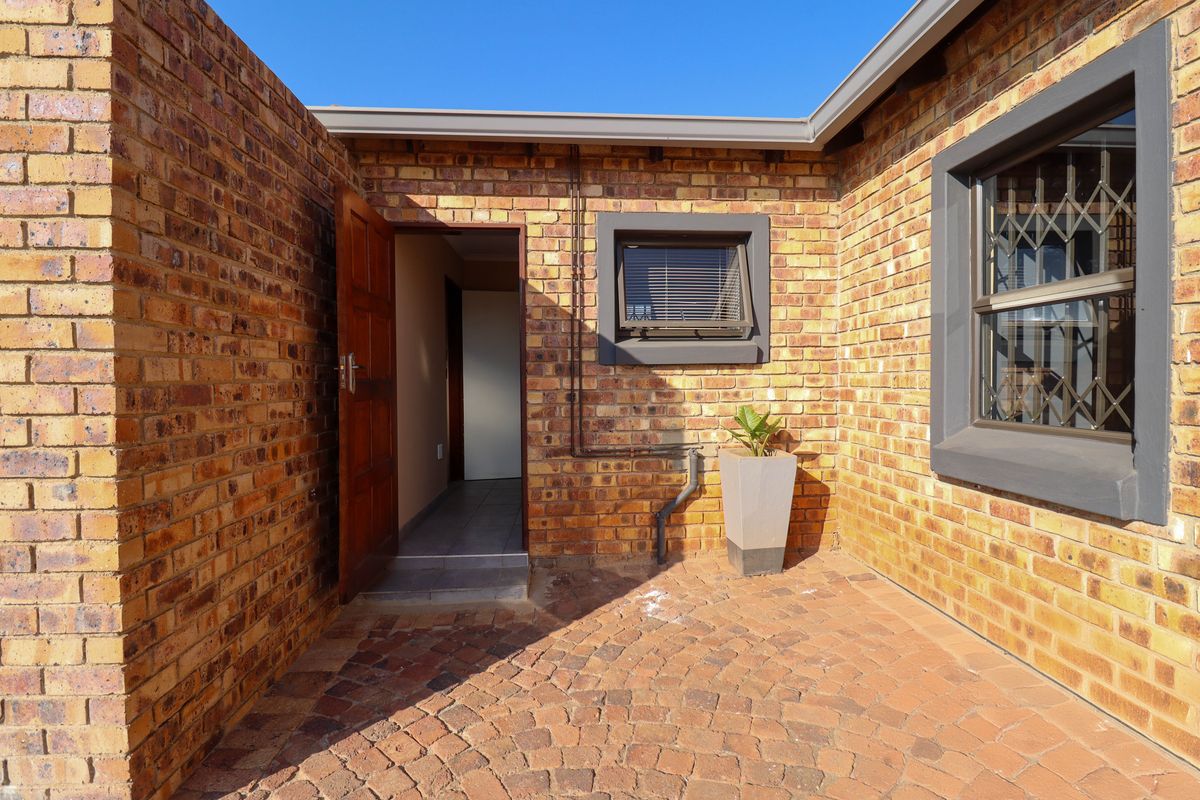 A private rear courtyard featuring face brick walls, paved flooring, and direct access to the interior through a timber door.