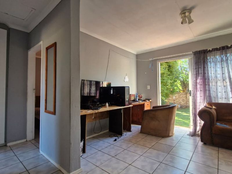 Living area featuring tiled flooring, a sliding glass door providing garden access, and a built-in cupboard, offering potential for modernization and improved layout.