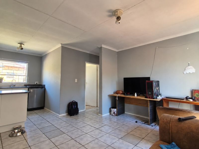 Open plan living and kitchen area featuring tiled flooring, neutral wall finishes, and functional kitchen cabinetry.