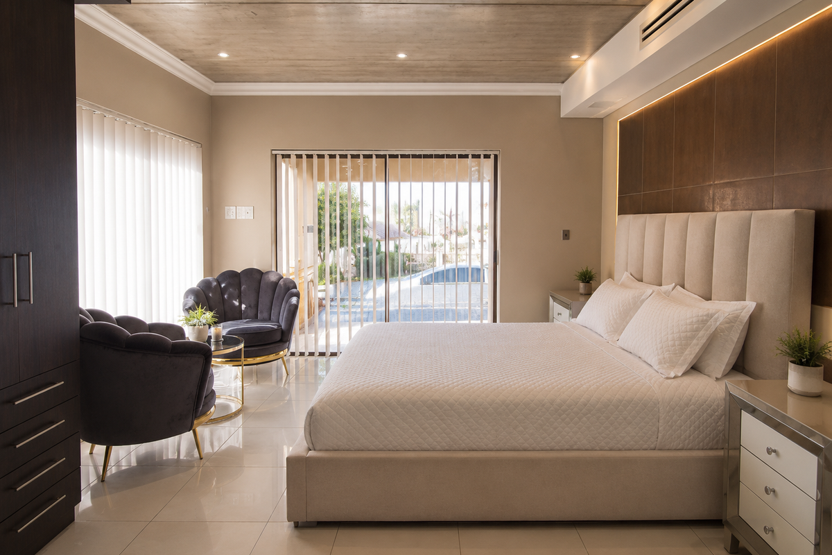 A modern, well-appointed bedroom featuring tiled floors, recessed lighting, ducted air conditioning, and a sliding door leading to an outdoor area.