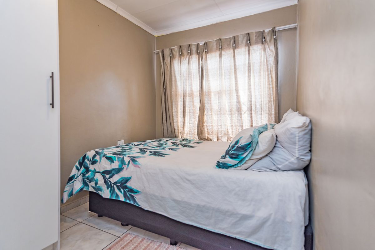 A compact bedroom featuring tiled flooring, a built-in wardrobe, and neutral wall tones, offering a functional and well-maintained living space.