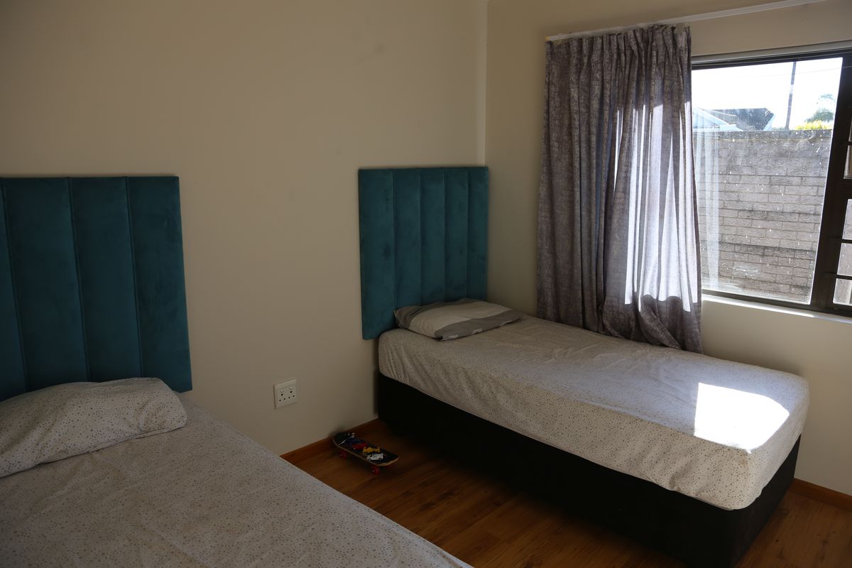 A bedroom featuring laminate flooring and a window with curtains, providing natural light.