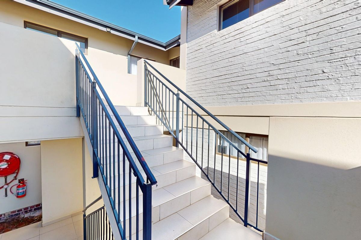 An exterior staircase with tiled steps and metal railings providing access between levels of the townhouse complex.