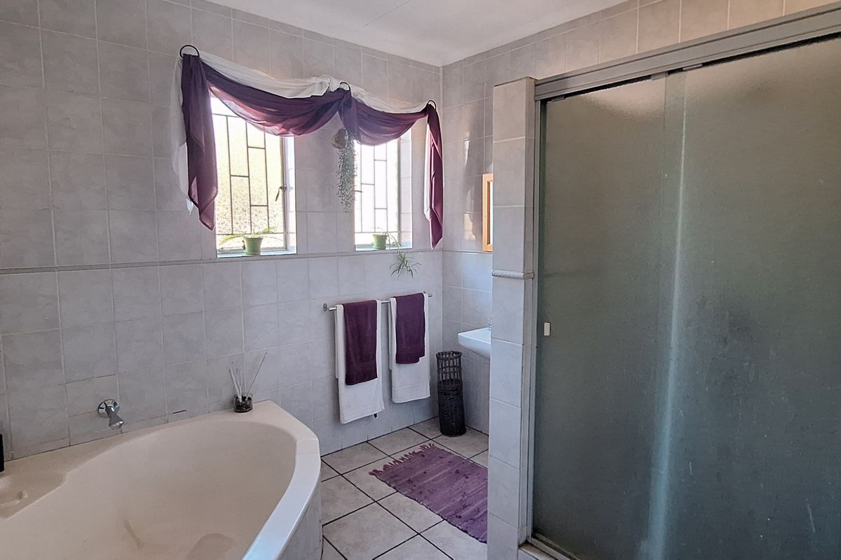A functional bathroom featuring a corner bathtub, a separate shower enclosure with frosted glass doors, and tiled wall and floor finishes.