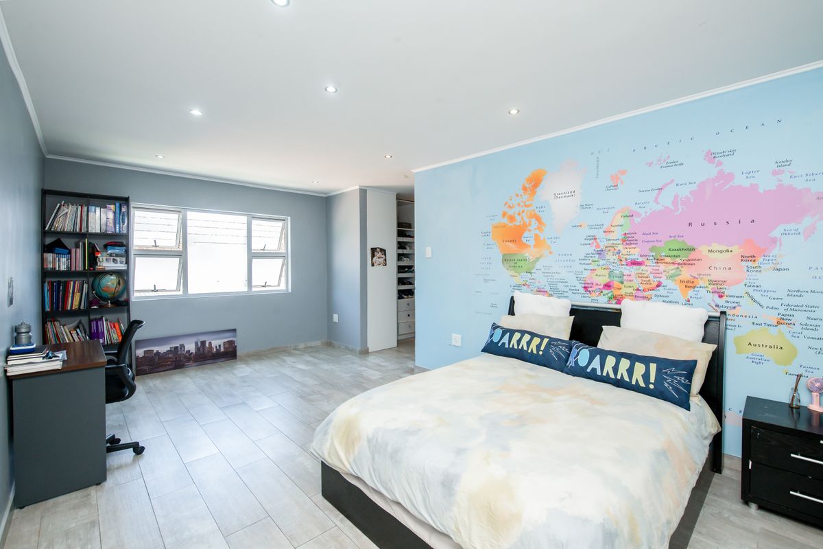 Spacious bedroom featuring tiled flooring, recessed ceiling lighting, and a large feature wall with a world map mural.