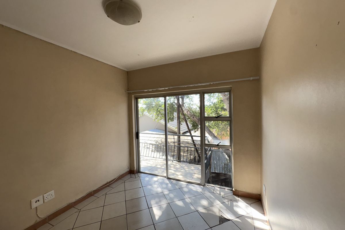 An empty bedroom featuring tiled flooring, a ceiling light fixture, and a sliding glass door providing access to an outdoor area.