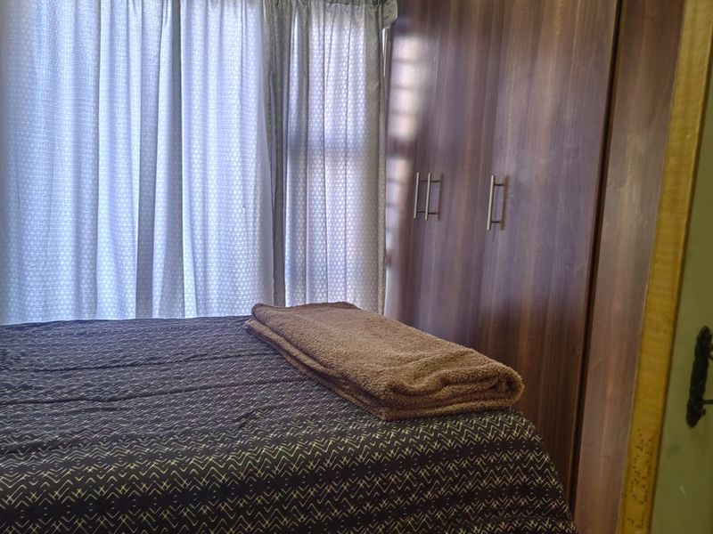 A bedroom featuring built-in wooden cupboards and tiled flooring, providing functional storage space.