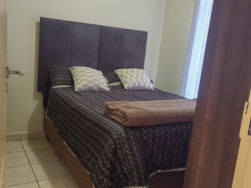 A compact bedroom featuring tiled flooring and a window, providing a functional sleeping space.