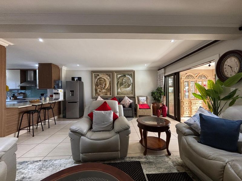 Spacious open-plan living area featuring tiled flooring, recessed lighting, and a functional kitchen with an island, seamlessly connecting to the outdoor patio space.