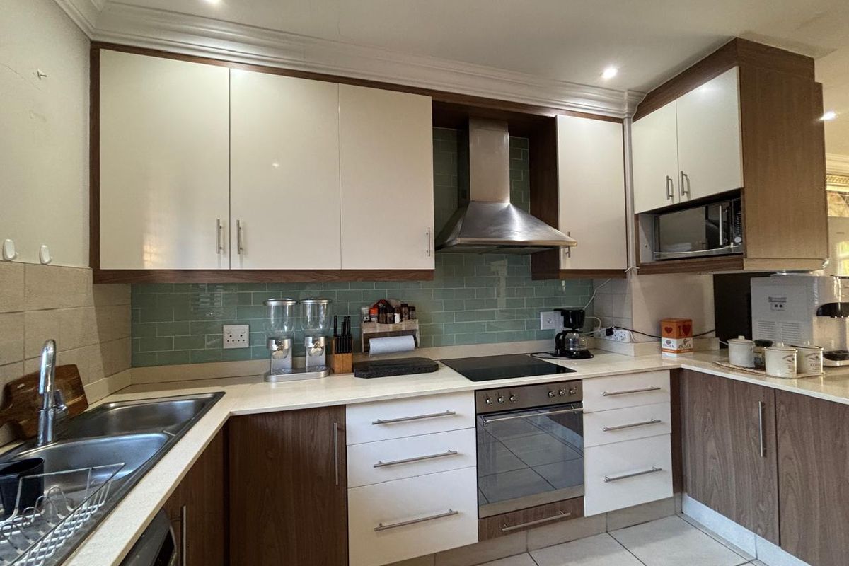 Modern kitchen featuring two-tone cabinetry, stone countertops, subway tile backsplash, and integrated stainless steel appliances including an oven, hob, and extractor fan.