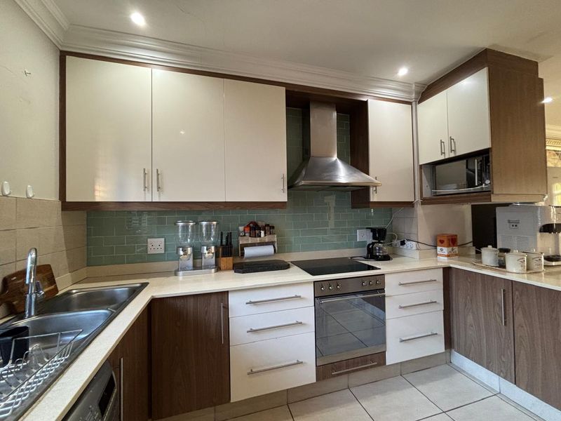 Modern kitchen featuring two-tone cabinetry, stone countertops, subway tile backsplash, and integrated stainless steel appliances including an oven, hob, and extractor fan.