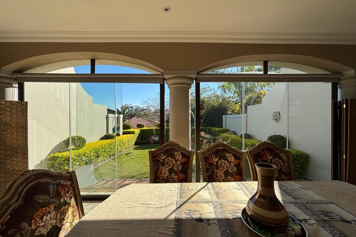 A bright living area featuring large glass stacker doors that provide seamless access and views to the landscaped garden and patio.
