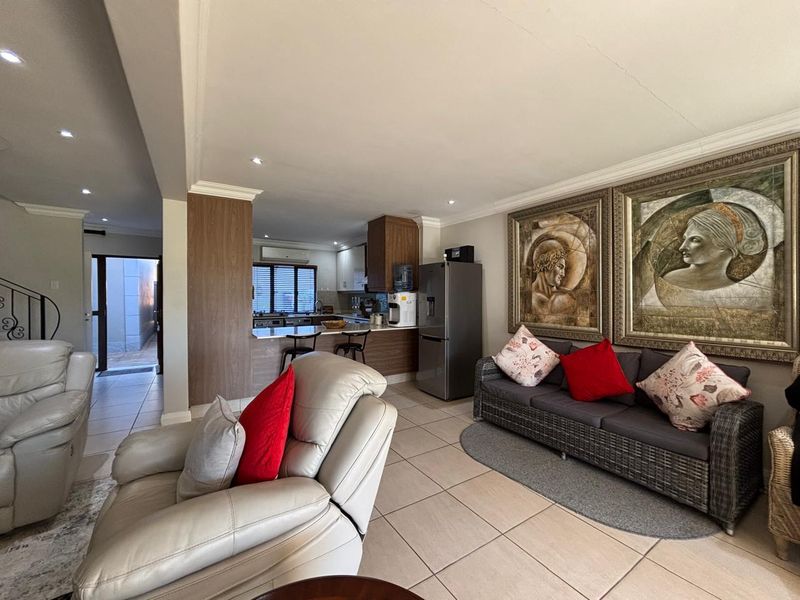 Open-plan living area featuring tiled floors, recessed lighting, and a functional kitchen with built-in cabinetry, breakfast bar, and integrated appliances.