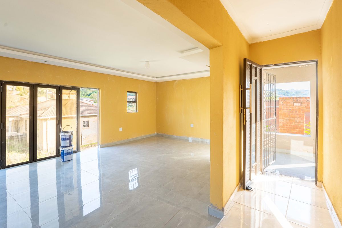 An empty, open-plan living area featuring polished tiled floors, recessed ceiling details, and large sliding glass doors leading to an outdoor space.