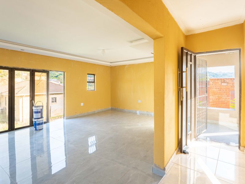 An empty, open-plan living area featuring polished tiled floors, recessed ceiling details, and large sliding glass doors leading to an outdoor space.