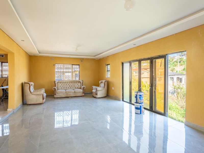 Spacious living room featuring large porcelain floor tiles, a recessed ceiling tray, and aluminium stacker doors opening to the exterior.