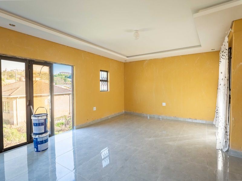 An empty living room featuring tiled floors, recessed ceiling detail, and sliding glass doors leading to the exterior.