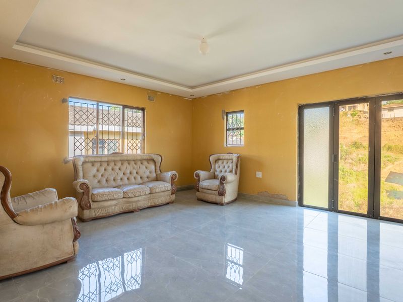 Spacious living room featuring tiled flooring, recessed ceiling, and sliding glass doors leading to the exterior, requiring cosmetic updates to the wall finishes.