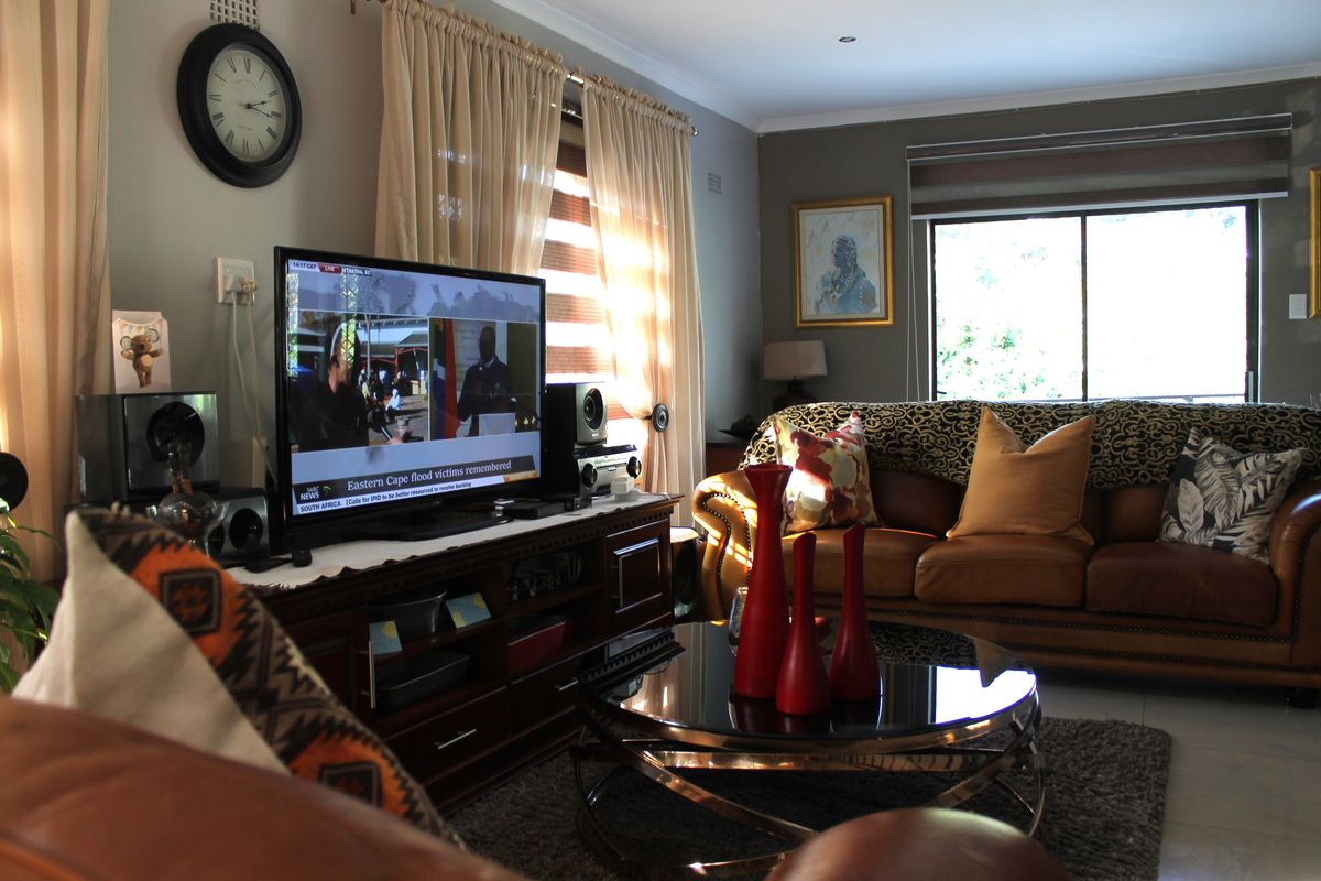 A comfortable living room featuring tiled flooring, recessed downlighting, and a large sliding glass door providing natural light.