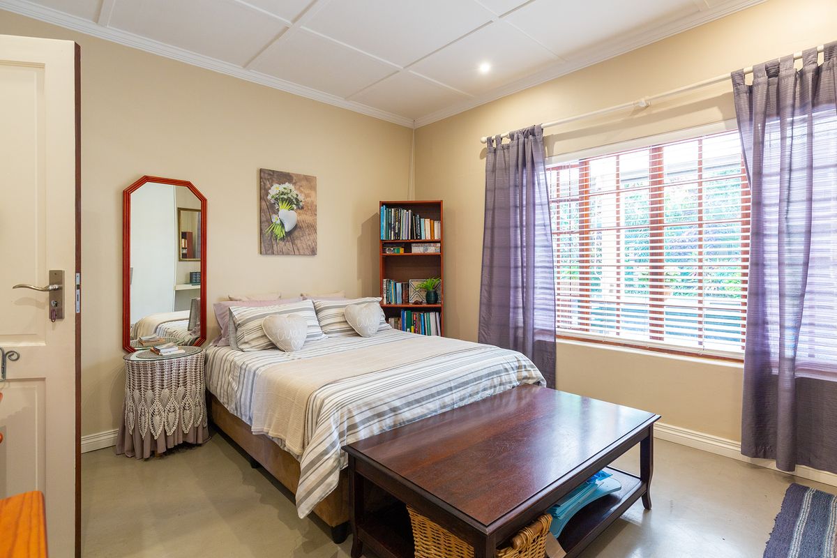 A well-maintained bedroom featuring tiled flooring, timber window frames with venetian blinds, and classic ceiling panel detailing.