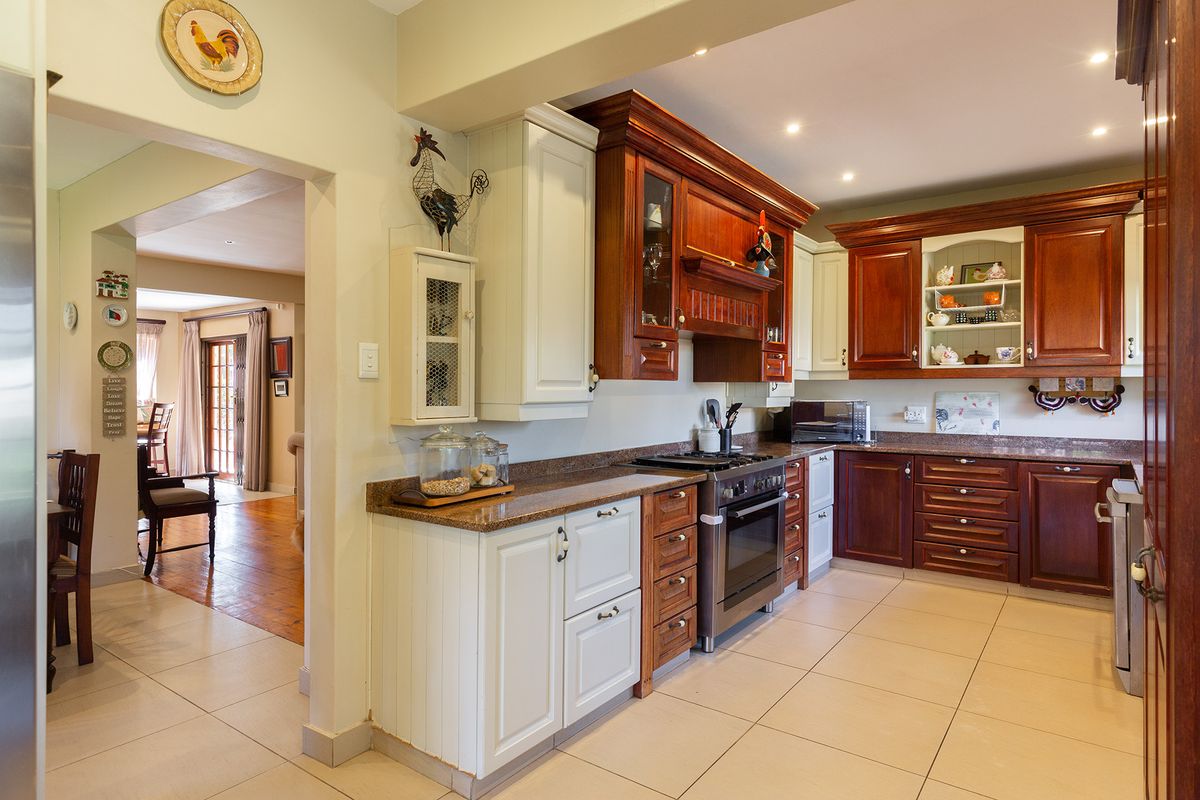A well-maintained kitchen featuring a mix of white and wood-toned cabinetry, granite countertops, and a gas stove, with an open flow to the dining area.
