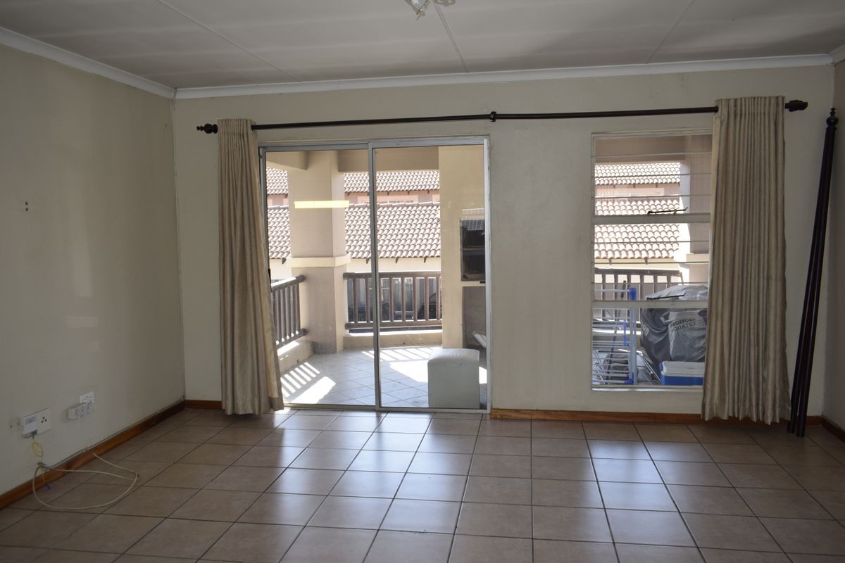 Spacious living area featuring neutral tiled flooring and large sliding glass doors providing access to an outdoor balcony.