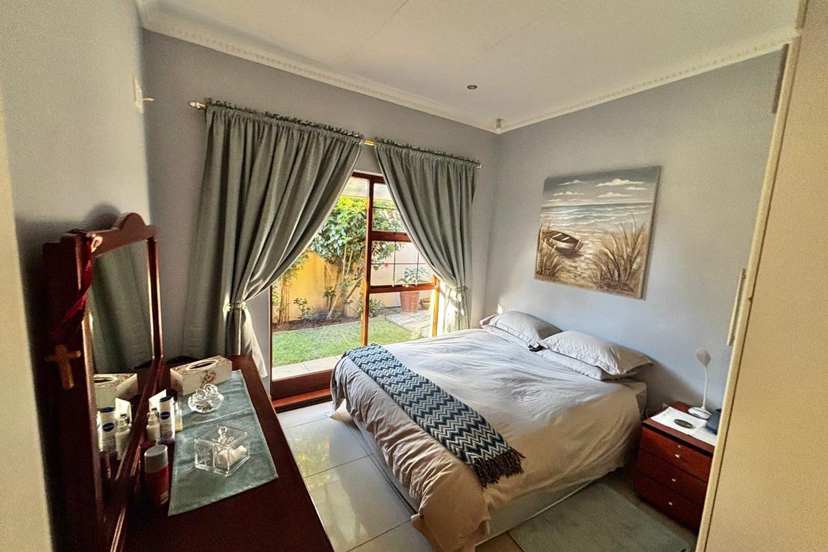 A well-maintained bedroom featuring tiled flooring, crown molding, and a sliding glass door providing direct access to a private garden area.